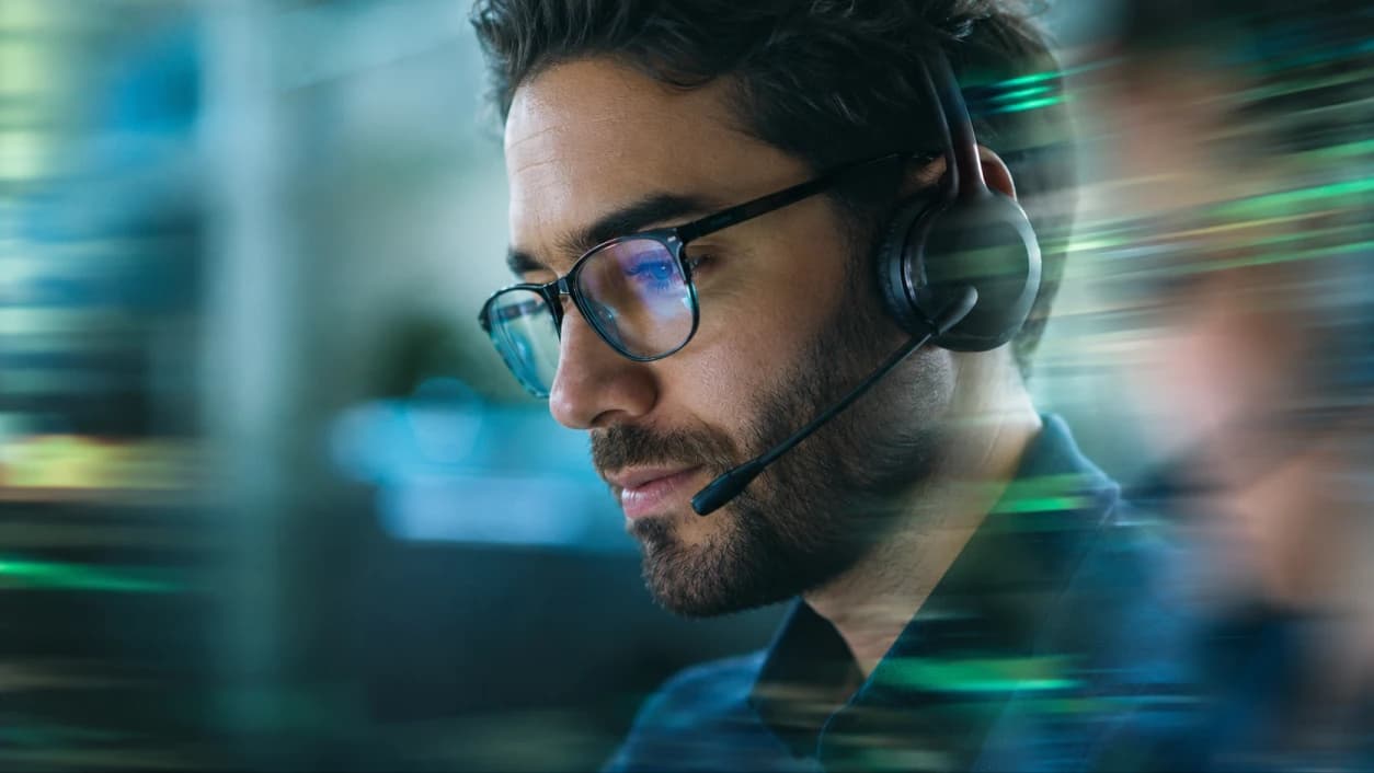 Contact center agent in a headset, focused on their monitor